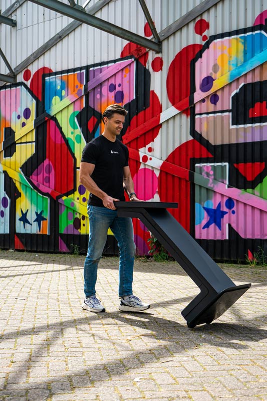Un membre de l'équipe déplace facilement un Onesix Kiosk devant un mur de graffitis