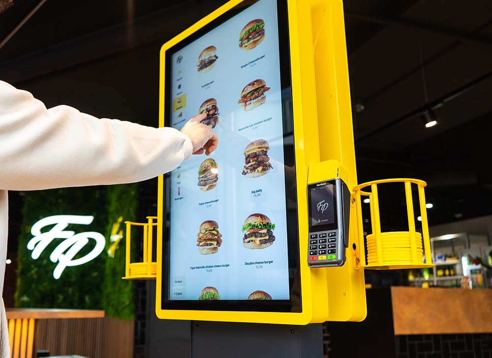 Un client commande sur le Onesix Kiosk jaune chez Fat Phill's